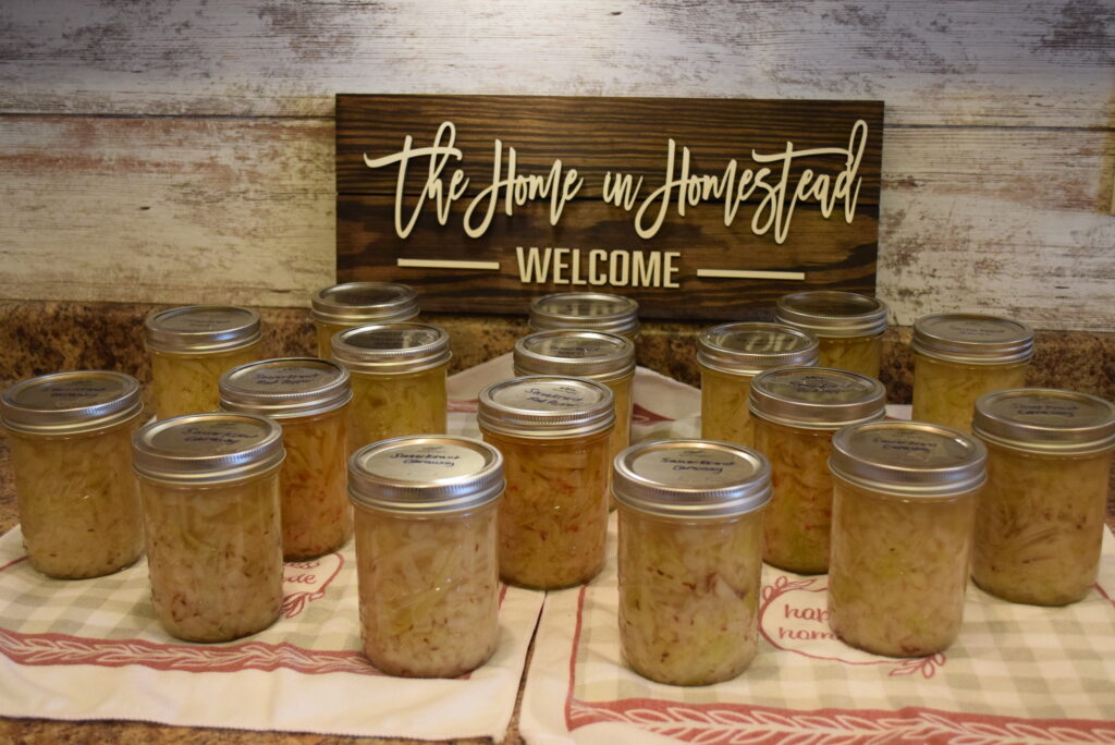 Various Flavored Homemade Sauerkraut in Mason Jars - in front of The Home in Homestead Sign