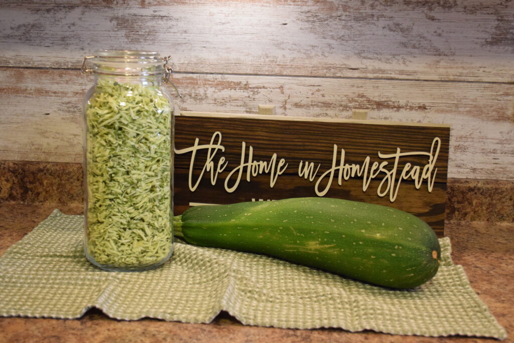 Freeze Dried Shredded Zucchini in a Glass Jar in front of a The Home in Homestead sign
